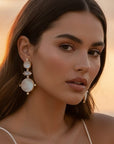 d-by-dalia-jewelry tiered drop earrings featuring iridescent mother-of-pearl and crystals on a woman at sunset