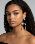 Model wearing d-by-dalia-jewelry silver-tone chandelier drop earrings with icy blue crystals and crescent accents.