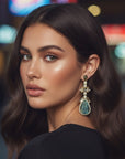 d-by-dalia-jewelry statement drop earrings with carved teardrop gemstone, crystal halo, and gold setting on a model.